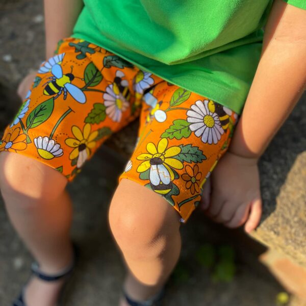 Image shows close up of child wearing retro spring bee shorts and plain green tshirt