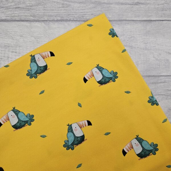 This Toucan Jersey Fabric is on a bright yellow background which gives a joyful contrast to the sage green of the hand drawn toucans. A repeating directional design